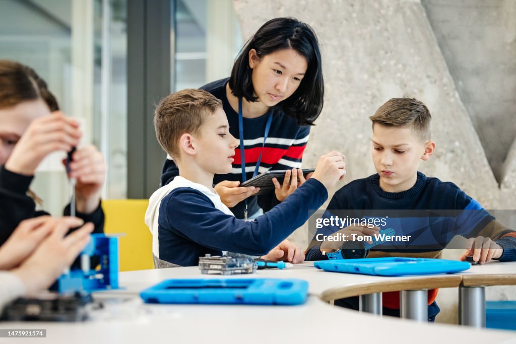 Teacher Helping Young Students With Mechanical Task During Tech ...