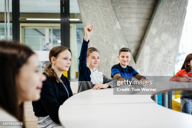 young boy raising hand to ask question at tech workshop - atelier enfant photos et images de collection