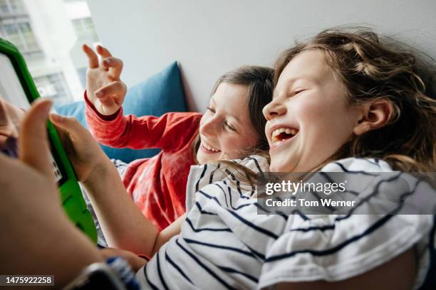 two young girls laughing while playing on digital tablet - 8 muses stock pictures, royalty-free photos & images