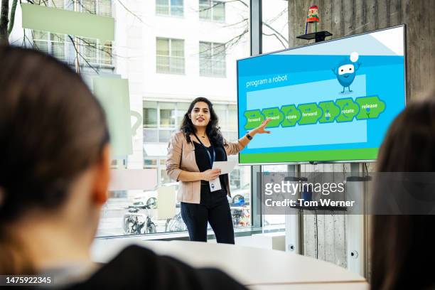 teacher giving presentation and pointing at monitor during tech workshop for kids - big screen stock-fotos und bilder