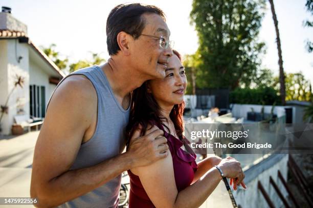 mature couple enjoying view from patio at vacation rental home - mature asian woman candid foto e immagini stock