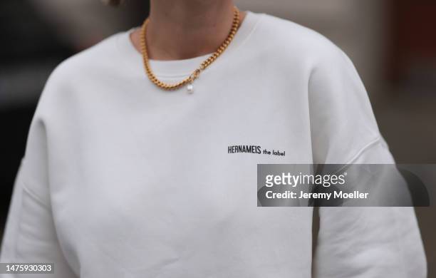 Victoria Thomas seen wearing Ariane Ernst gold necklace, Hernameis white oversized sweater with back print on March 20, 2023 in Cologne, Germany.