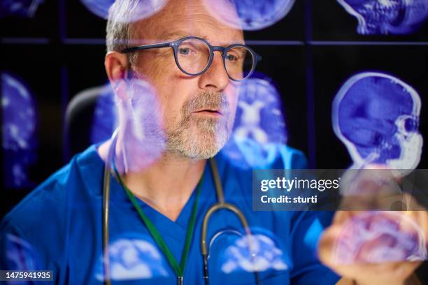 chirurg, der gehirnscans beurteilt - hirntumor stock-fotos und bilder