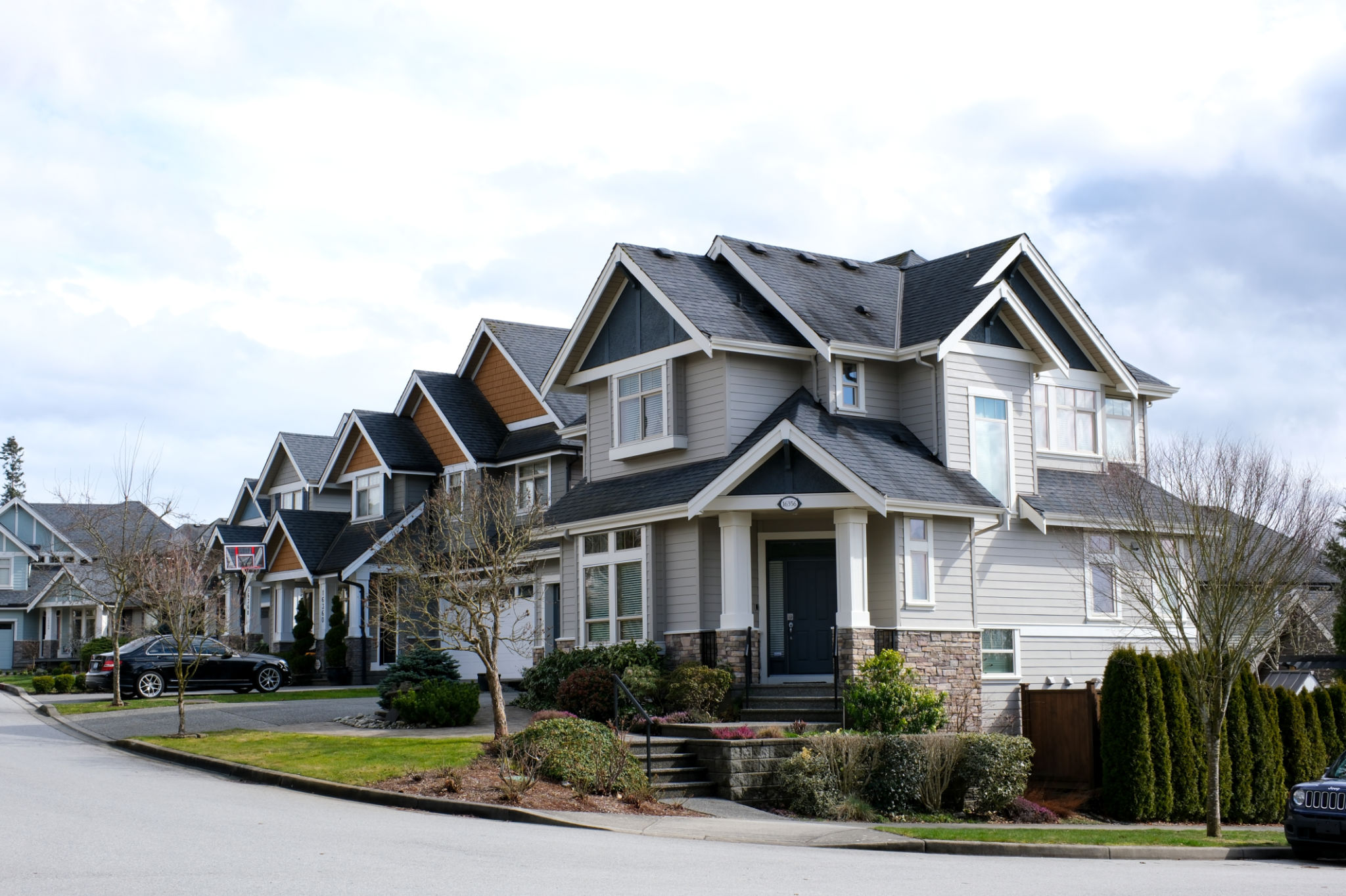 A row of a new houses in Surrey British Columbia, Canada. Front yards of the houses and street with trees and bushes. A row of a new houses in Surrey British Columbia, Canada. Front yards of the houses and street with trees and bushes.
