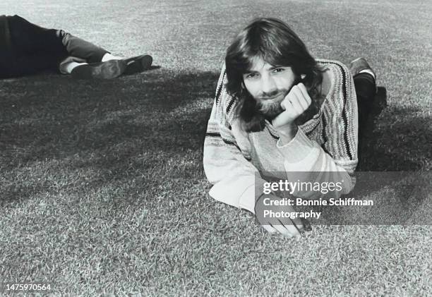 Musician Kenny Loggins lays on his stomach on grass, with his chest propped up and his head in his hand in Los Angeles in 1987.