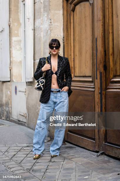 Gili Biegun wears sunglasses, earrings, a black and white studded large bag by Valentino, a black leather belt by Hermes, golden pump shoes by...