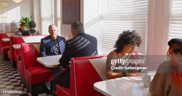 customers sitting in booths in 1950s styled diner - american diner stock pictures, royalty-free photos & images