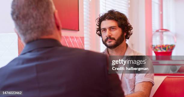 over the shoulder shot of man talking to two men in suits in 1950s styled diner - booth bildbanksfoton och bilder