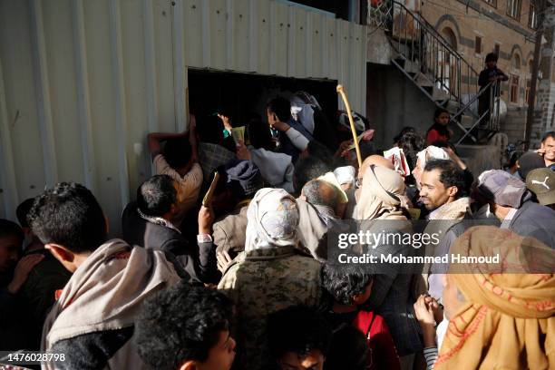 People affected by eight years of war and blockade receive free meals provided by a charitable kitchen in the Mseek area on March 23, 2022 in Sana'a,...