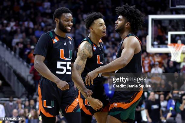 Wooga Poplar, Jordan Miller and Norchad Omier of the Miami Hurricanes celebrate after defeating the Houston Cougars 89-75 during the Sweet 16 round...