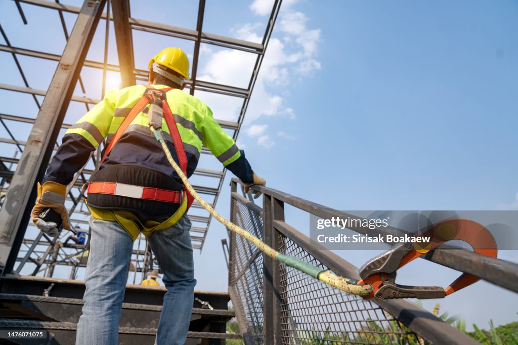 Construction worker wearing safety harness belt during working at high place,
