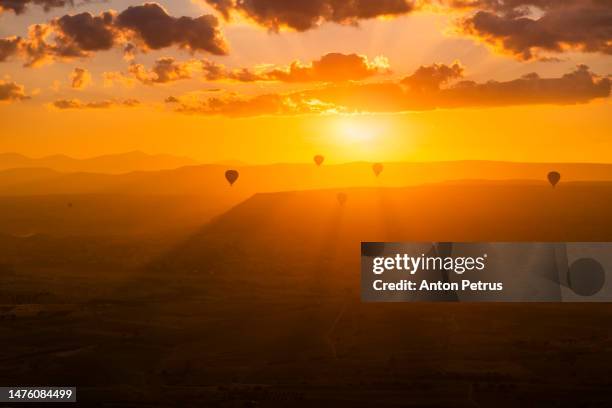 hot air balloons at sunrise over the landscape in cappadocia, turkey - cave fire stock pictures, royalty-free photos & images