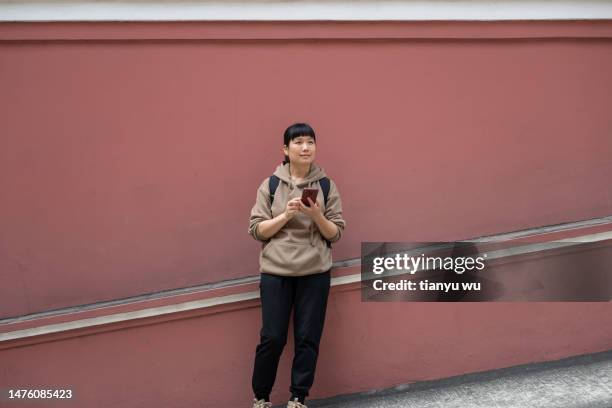 eine touristin schaut mit ihrem handy an der straßenmauer - portraits fun mobile wall stock-fotos und bilder