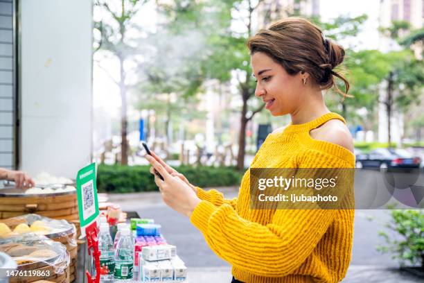 young female customer using digital payment method, scanning qr code with smartphone - código-de-barras imagens e fotografias de stock