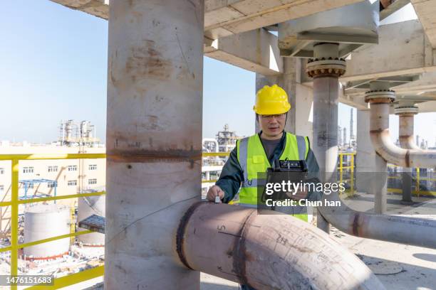 a male worker tests with an instrument in a chemical factory - chemische fabriek stockfoto's en -beelden