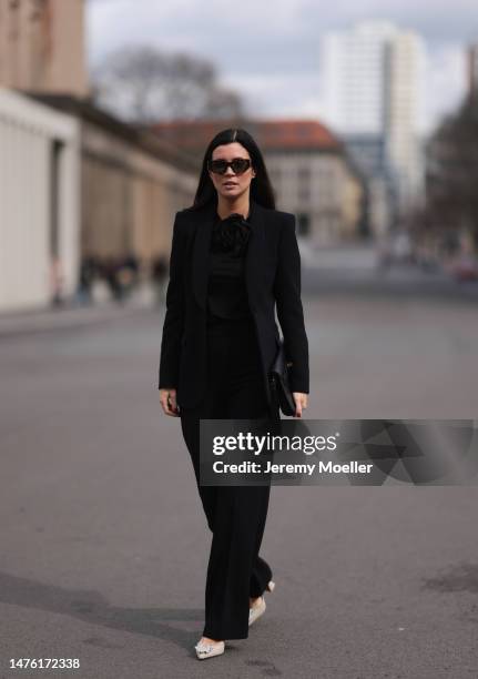 Leo Eberlin is seen wearing YSL brown sunglasses, Leo Mathild diamond jewellery, Zara black rose top, Zara black blazer and matching black suit...