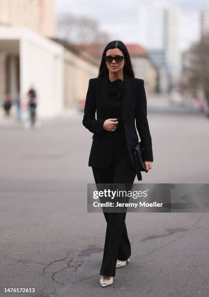 Leo Eberlin is seen wearing YSL brown sunglasses, Leo Mathild diamond jewellery, Zara black rose top, Zara black blazer and matching black suit...