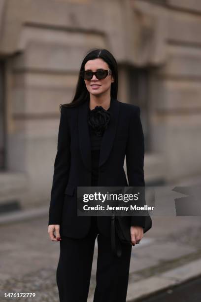 Leo Eberlin is seen wearing YSL brown sunglasses, Leo Mathild diamond jewellery, Zara black rose top, Zara black blazer and matching black suit...