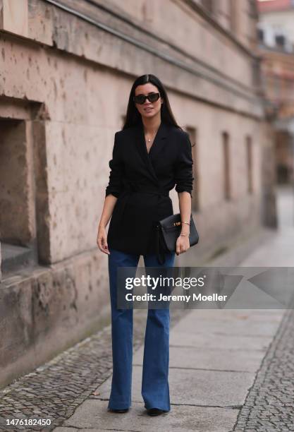 Leo Eberlin is seen wearing YSL brown sunglasses, Leo Mathild diamond jewellery, Toteme black blazer, Veronica Beard blue denim pants, Valentino...