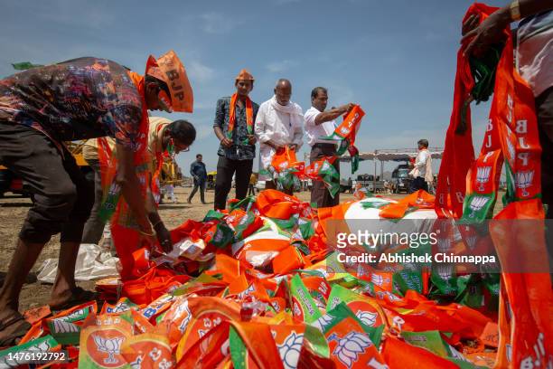 Men pick up saffron coloured scarfs and caps as they arrive to attend a political event organised by the Bharatiya Janata Party and addressed by...