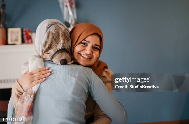 portrait of young smiling women hugging during ramadan - ramadan greeting stock pictures, royalty-free photos & images