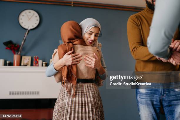 ein lächelndes paar empfängt seinen gast während des ramadan in seinem haus - familientreffen stock-fotos und bilder