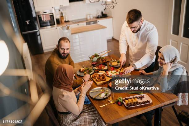 vue en hauteur de deux jeunes couples musulmans assis ensemble tout en dégustant un repas pendant le ramadan - iftar photos et images de collection