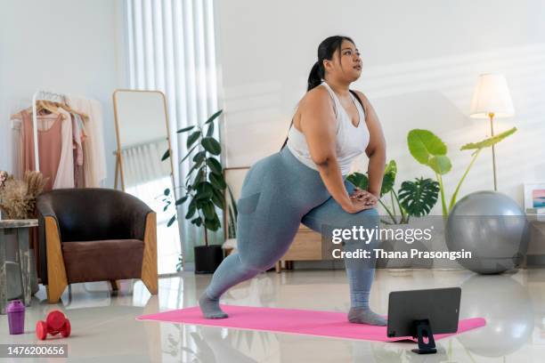 young woman doing yoga virtual fitness class with laptop at hom - hom stock pictures, royalty-free photos & images