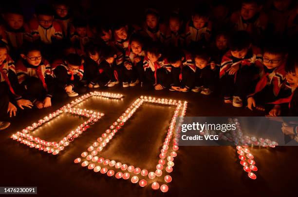 Students light candles to form semiotics of 60 to mark the Earth Hour environmental campaign at a primary school on March 24, 2023 in Handan, Hebei...