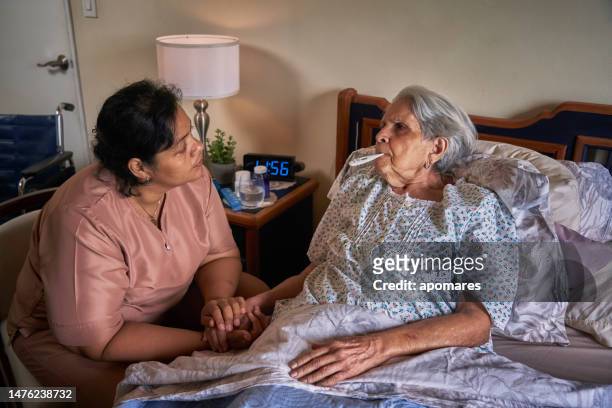 krankenschwester misst körpertemperatur für eine hispanische ältere frau zu hause mit digitalem messgerät - hot nurse stock-fotos und bilder