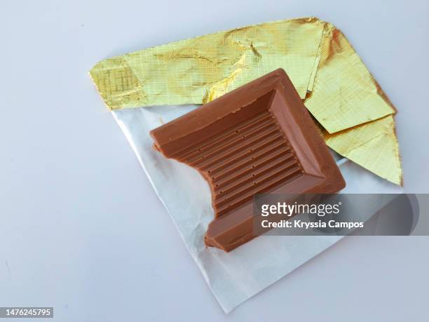 chocolate bar with bite in gold foil - candy wrapper stock-fotos und bilder