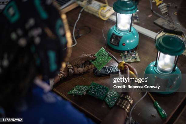 Indian villager Chandrakanta Sen assembles a circuit board for a solar lamp in a class held as part of the Barefoot Solar Project to bring solar...