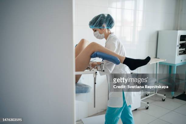 woman doctor gynecologist examines a patient on a gynecological chair - papanicolau fotografías e imágenes de stock