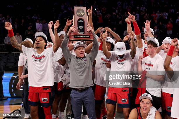 Head coach Dusty May of the Florida Atlantic Owls hoist the trophy with the team after defeating the Kansas State Wildcats in the Elite Eight round...