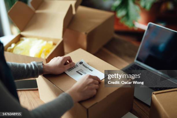 close-up of female hand attaching shipping labels onto parcel box - arranging products stock pictures, royalty-free photos & images