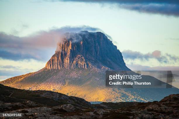 hoher berg in zerklüfteter landschaft im goldenen morgenlicht - cradle mountain stock-fotos und bilder
