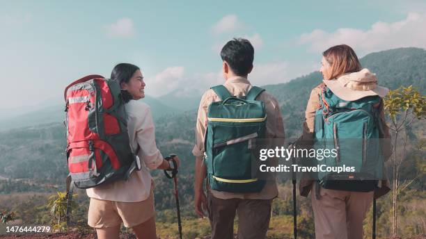 rear view three friends hikers with backpacks enjoying trekking day on mountain. carefree climbing tourists raised arms looking at horizon. freedom. success sport concept - womens champions day three stock pictures, royalty-free photos & images