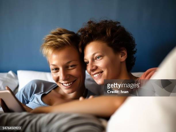 latin caucasus woman embracing female partner with closed eyes while lay on bed - latin american stock-fotos und bilder