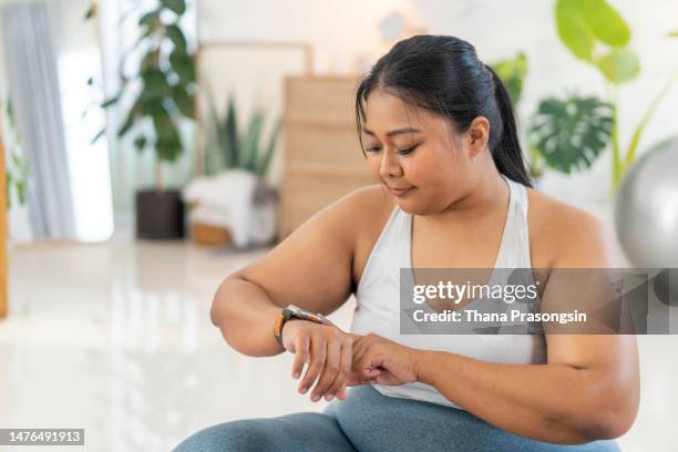young woman checking her fitness activity on a smartwatch - fitness tracker stock-fotos und bilder