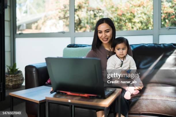 eine frau, begleitet von ihrer tochter, die von zu hause aus hybride arbeit verrichtet. - maori family stock-fotos und bilder