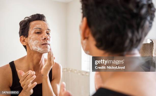 reflection in bathroom mirror of a person washing their face with soap in bathroom - body scrub bildbanksfoton och bilder