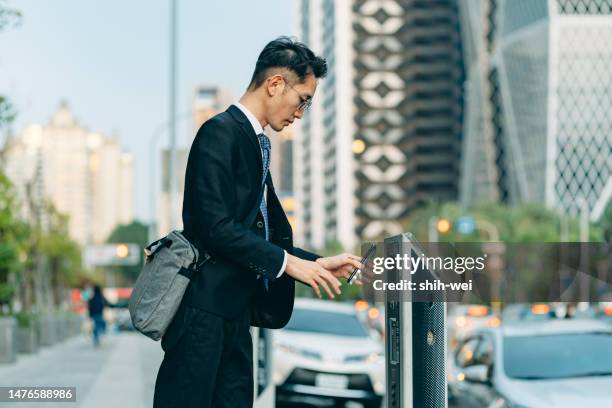 uomo d'affari asiatico in città che effettua il pagamento mobile per il parcheggio - città intelligente foto e immagini stock