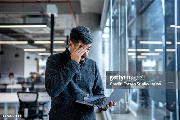 uomo maturo preoccupato che usa il computer portatile che lavora in ufficio - mistake foto e immagini stock