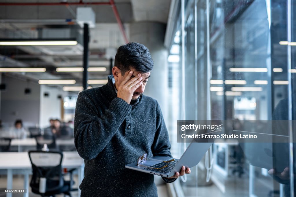 Worried mature man using laptop working at office