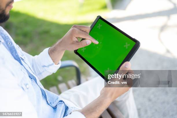 man using digital tablet with chroma key in park - finger scrolling stock pictures, royalty-free photos & images