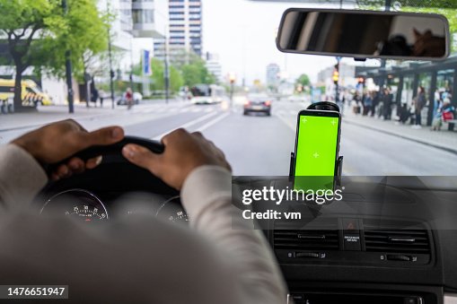 窓にスマートフォンを付けて車を運転する男性 窓にスマートフォンを付けて車を運転する男性