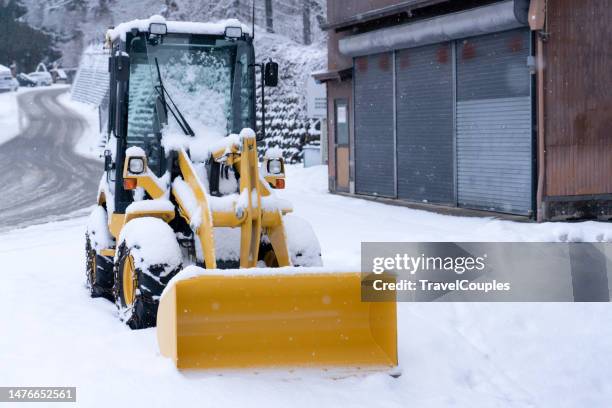 tractor sweeping the street. snow removal vehicle removing snow. backhoe was parked on the side of the road. it is to be used to shovel snow that falls on the road blocking traffic during a snowstorm. - removing stock pictures, royalty-free photos & images