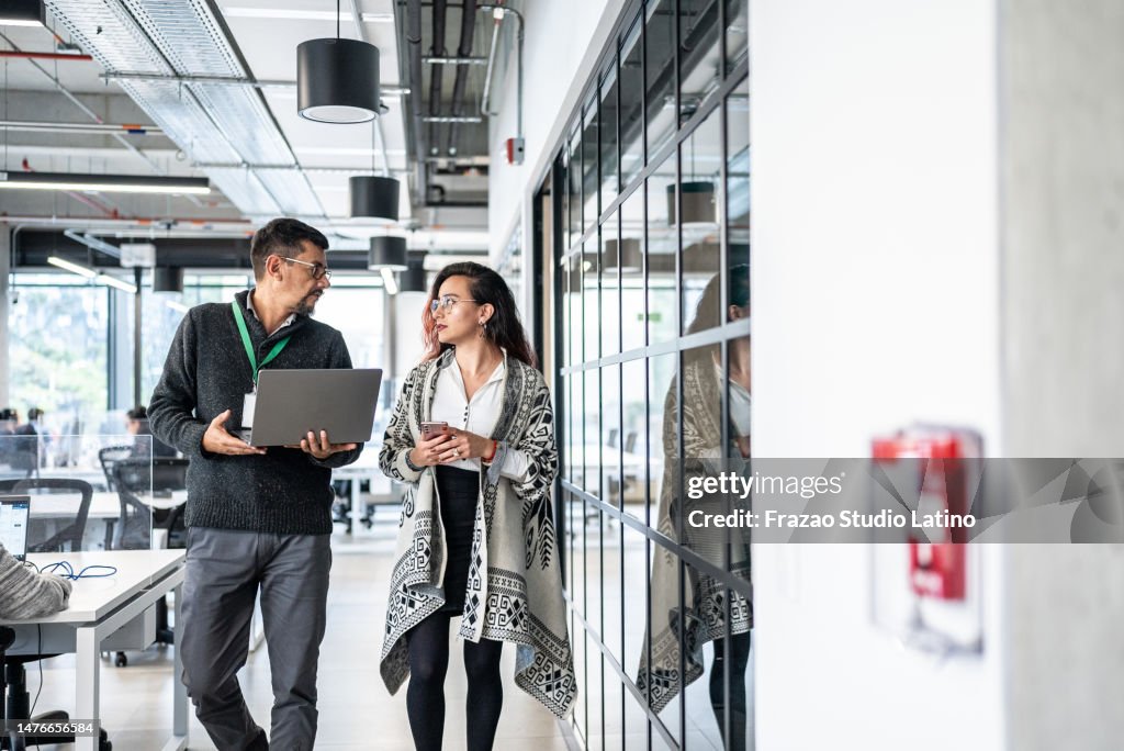 Coworkers talking while walk through office