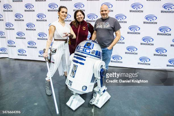 Star Wars cosplayer Jordan Giannini as Rey Skywalker and journalists Chris Morrow and Marty Morrow pose with an R2-D2 replica droid at Day 2 of...