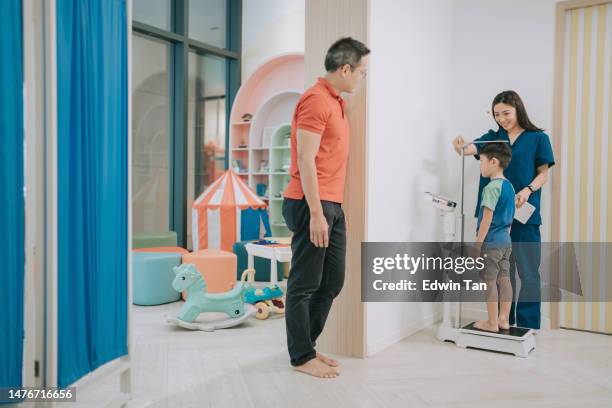 asiatisch-chinesische kinderkrankenschwester misst größe und gewicht eines kleinen jungen in der klinik - messlatte stock-fotos und bilder